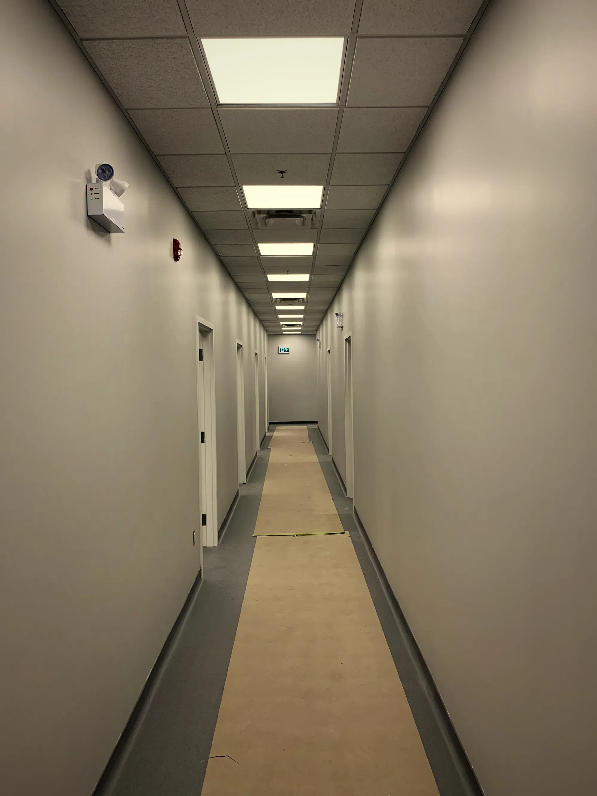 Lit common-area corridor running the length of a multifamily building.